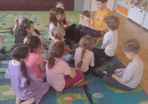 Dzieci z grupy V słuchają jak czyta absolwent naszego przedszkola