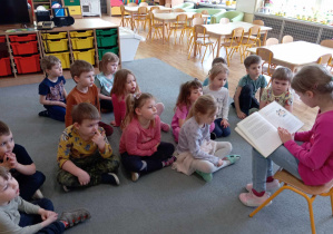 Dzieci z grupy II słuchają jak czyta absolwentka naszego przedszkola