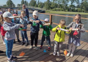 Dzieci nawijają plastikowe ryby na sznurek