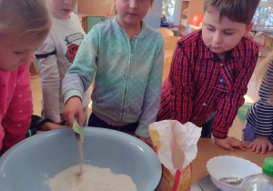 Dziewczynka dosypuje suche drożdże do ciasta na chleb